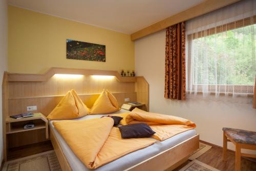 a bedroom with a bed with yellow sheets and a window at Ferienhaus Sonnenhang in Matrei in Osttirol