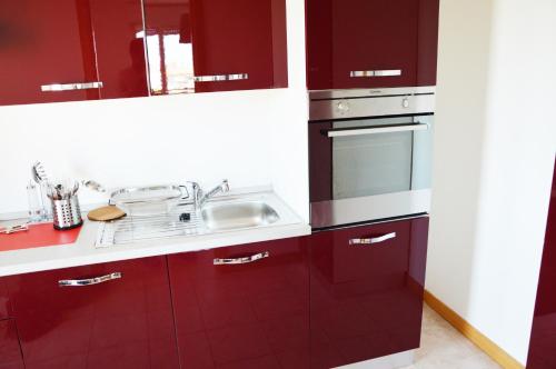 una cucina con armadi rossi e lavandino di Elegance ad Alba Adriatica