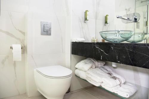 a bathroom with a toilet and a sink and towels at Napa Mermaid Hotel & Suites in Ayia Napa