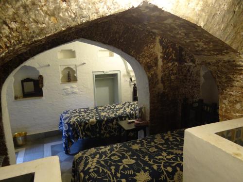 a bedroom with two beds in a stone wall at Labboo'z Café and Lodge in Maheshwar