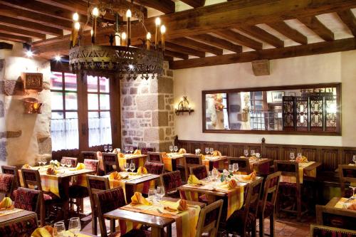 un restaurant avec des tables et des chaises en bois et un lustre dans l'établissement Auberge Saint Pierre, au Mont-Saint-Michel