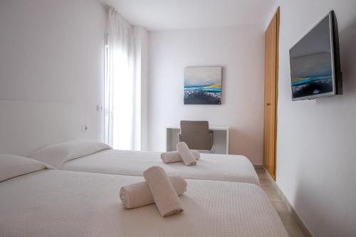 Sal Mar Suites في سانتا إيولاليا ديل ريو: غرفة نوم بسريرين عليها مناشف