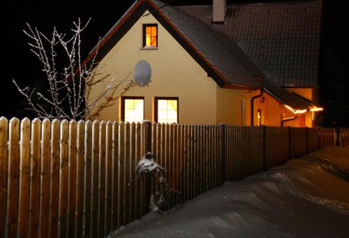a fence in front of a house with a window at Taneček - malý apartmán u rodinného domu in Stvolínky