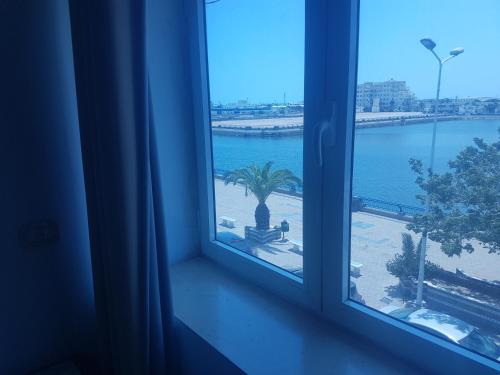 a window with a view of the ocean and a palm tree at Hotel El Layeli in Sfax