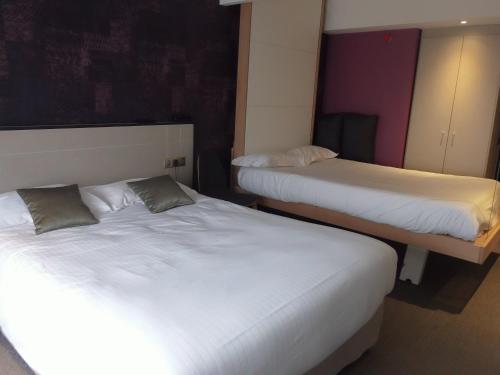 two beds in a room with white sheets at The Originals Boutique, Hôtel La Chaussairie, Rennes Sud in Chartres-de-Bretagne