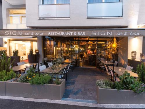 a restaurant with tables and chairs in front of a building at Hotel My Way Zürich Wallisellen in Wallisellen