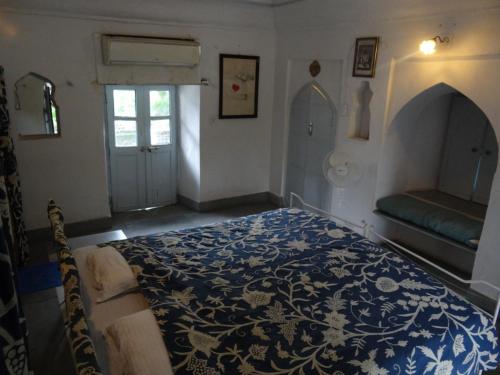 a bedroom with a blue and white bed and a window at Labboo'z Café and Lodge in Maheshwar