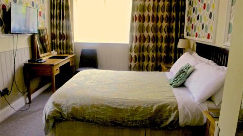 a hotel room with a bed and a desk and a window at Acorn Guest House in Hull in Hull
