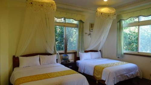 two beds in a room with two windows at Emoonten Homestay in Sanzhi