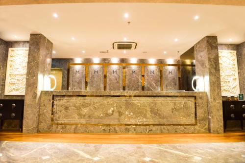 a lobby with a large gold wall with wooden doors at Moty Hotel in Melaka