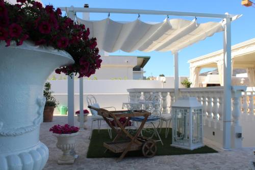 a white patio with a table and a cart with flowers at White House Luxury Hospitality in Olbia