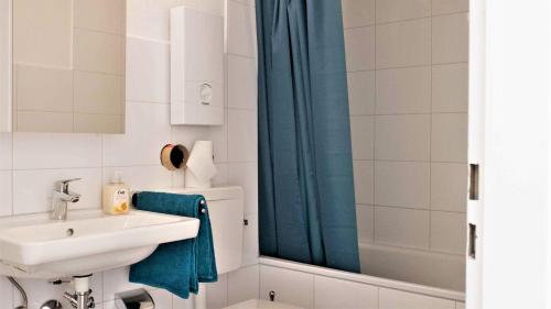 a bathroom with a sink and a blue shower curtain at Working & Longstay Apartments DD in Düsseldorf