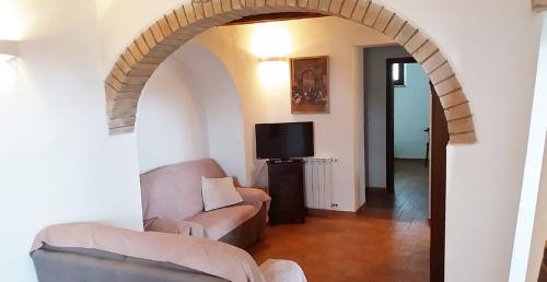 een boog in een woonkamer met een bank en een tv bij Casa dei Borghi in Murlo