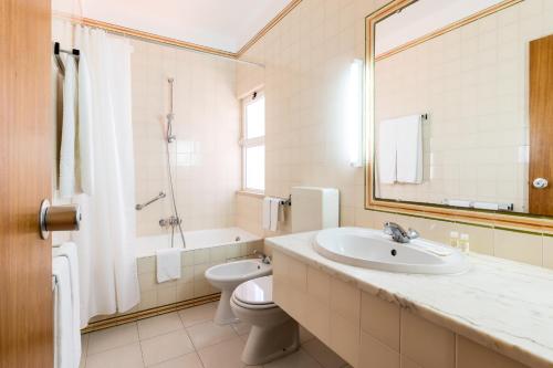 a bathroom with a sink and a toilet and a mirror at Apartamentos Turisticos Pinhal Da Marina in Vilamoura