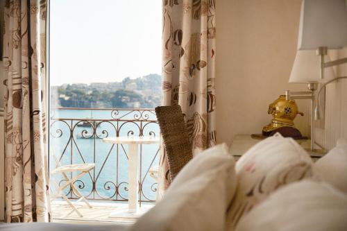a room with a balcony with a view of the water at Welcome Hotel in Villefranche-sur-Mer