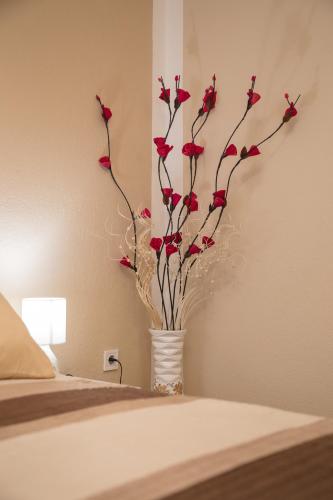 a vase filled with red flowers sitting on a bed at IRIS Room & Apartment in Slunj