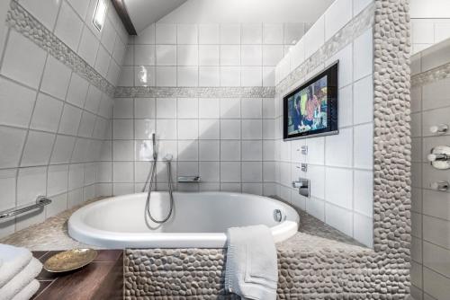 a white bathroom with a tub and a tv at Main Street Hotel in Ypres