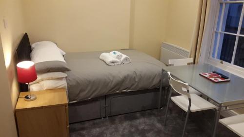 een kleine slaapkamer met een bed en een bureau bij Regents Street Studios in Leamington Spa