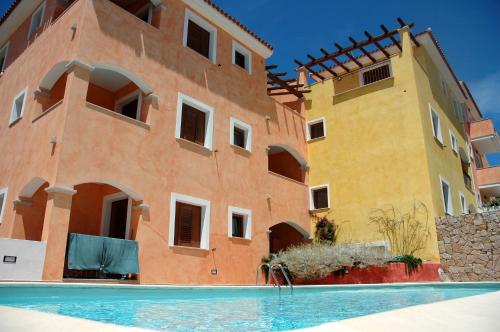 un bâtiment avec une piscine en face d'un bâtiment dans l'établissement Residence Dei Fiori, à Santa Teresa Gallura