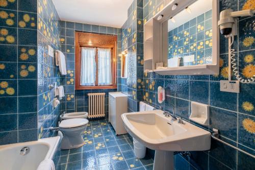 een blauw betegelde badkamer met 2 toiletten en een wastafel bij Hotel Al Larin in Cortina dʼAmpezzo