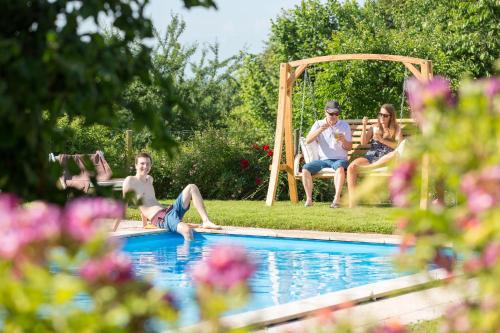 um grupo de pessoas sentadas ao redor de uma piscina em Landhaus Hoher em Oberteuringen