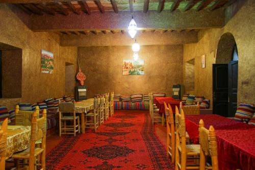 jadalnia ze stołami i krzesłami oraz czerwonym dywanem w obiekcie Skoura Lodge w mieście Skoura