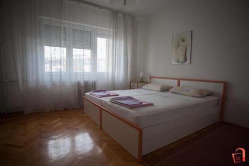 a bedroom with a large white bed with a window at Apartment Buzarovski in Skopje