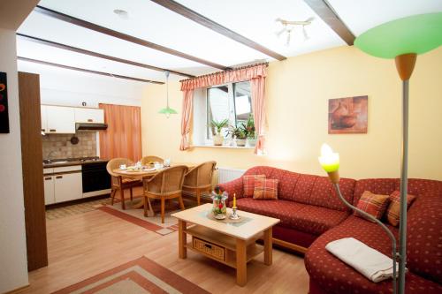a living room with a red couch and a table at Ferienapartments Schnibbe in Bad Lauterberg