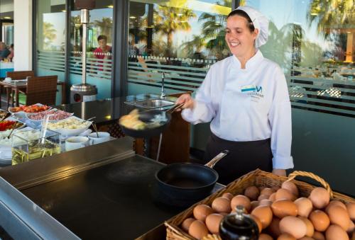 VidaMar Resort Hotel Madeira في فونشال: امرأة تحضر الطعام في مطبخ المطعم