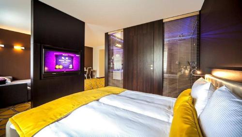 a bedroom with a large bed with a tv on the wall at Hotel Eclipse in Domasław