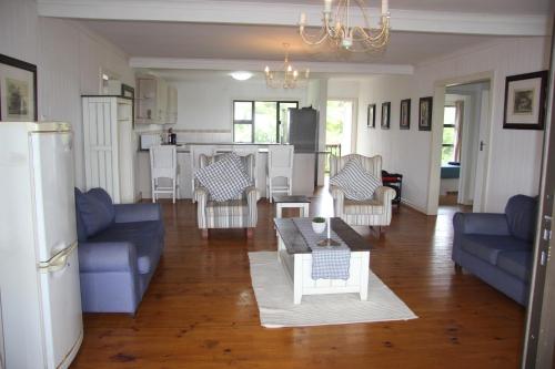 a living room with blue couches and a kitchen at Alfies House in Ponta Malongane