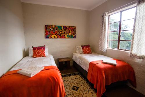 two beds in a room with a window at The Stix in Dullstroom