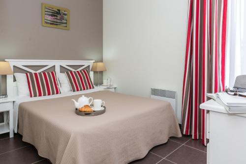 Un dormitorio con una cama con una bandeja de comida. en Résidence Prestige Odalys Le Clos Saint Michel, en Chinon