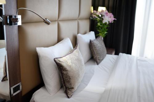 a bedroom with a white bed with pillows and a vase of flowers at Premier Hotel Dnister in Lviv