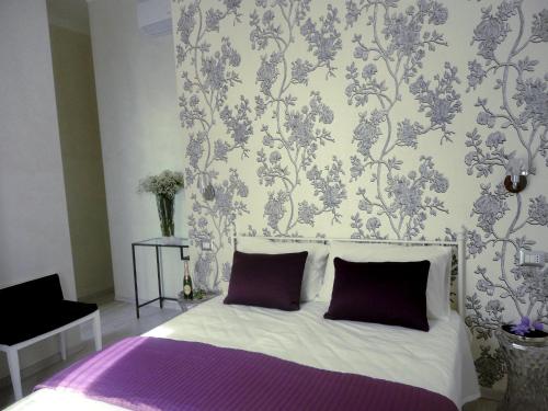 ein Schlafzimmer mit einem Bett mit lila Kissen und einer Tapete in der Unterkunft Cameo B&B in Rom