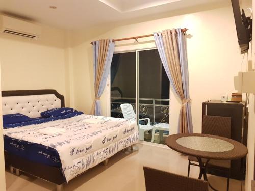 a bedroom with a bed and a table and a window at Bann Lom Le Guest House in Hua Hin