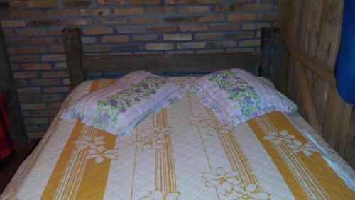 a wooden bed with two pillows on it at Pousada Recanto Da Fortaleza in Pedra