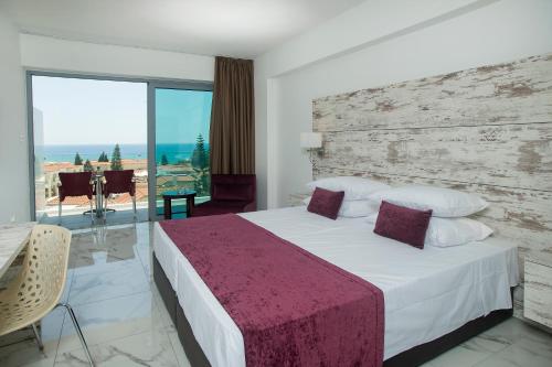 a bedroom with a large bed and a large window at Freij Beach Hotel Adults Only in Ayia Napa