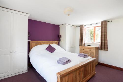 a bedroom with a large white bed with purple walls at Old Sheepcote in Broadway