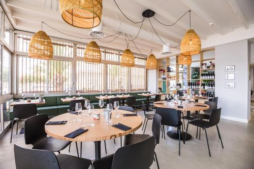 a restaurant with tables and chairs and windows at Hôtel Café Miramar in Le Grau-du-Roi