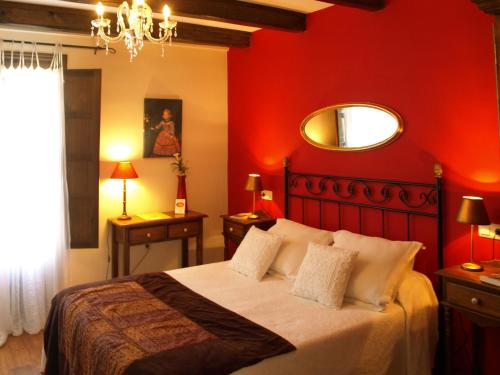 a bedroom with a bed with red walls and a mirror at Casa del Infanzón in Sos del Rey Católico