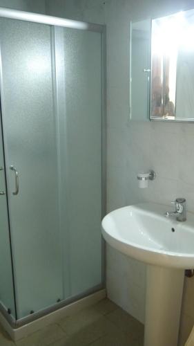 y baño con ducha acristalada y lavamanos. en Kruja Hotel, en Tirana
