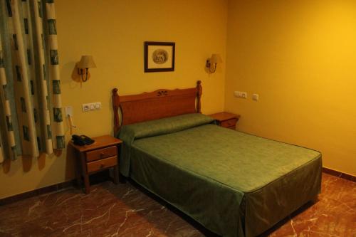 - une chambre avec un lit doté d'un couvre-lit vert et d'une table dans l'établissement Hotel Albohera, à Santiago de la Ribera