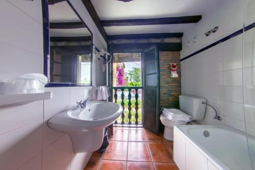 a bathroom with a sink and a tub and a toilet at Apartamentos Camino del Norte in Cóbreces