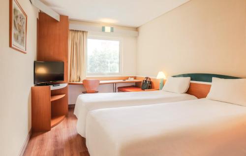 ein Hotelzimmer mit 2 Betten und einem TV in der Unterkunft Ibis Monterrey Aeropuerto in Monterrey