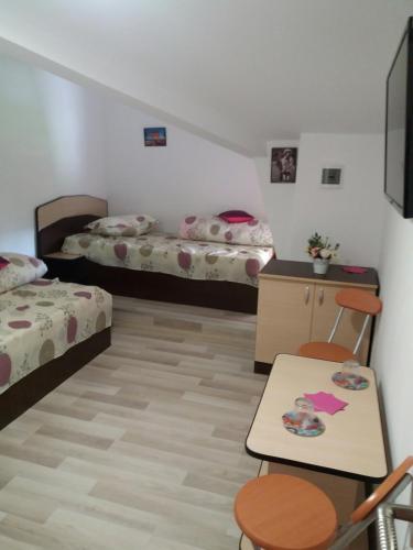 a room with two beds and a table and chairs at Casa Ariana in Curtea de Argeş