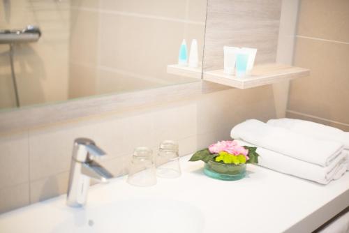 a bathroom sink with a vase of flowers and towels at Hotel Pommern in Mariehamn