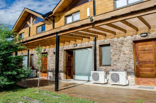 a brick house with a wooden door and a patio at Blackstone Country Villages Hotel in Villa General Belgrano