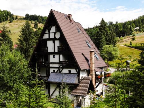 una casa en blanco y negro con techo marrón en Pensiunea Casa Noastra en Arieşeni