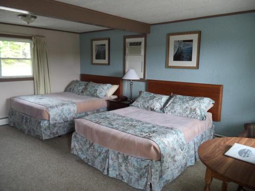 ein Hotelzimmer mit 2 Betten und einem Tisch in der Unterkunft Mount Blue Motel in Farmington